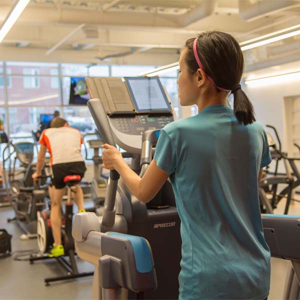 A woman adjusts an elliptical