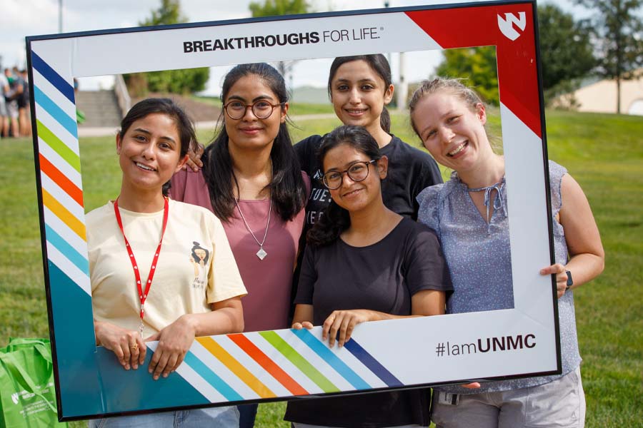 Five female students pose in a UNMC branded frame
