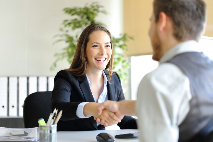 a young woman shakes the hand of an employer during an interview