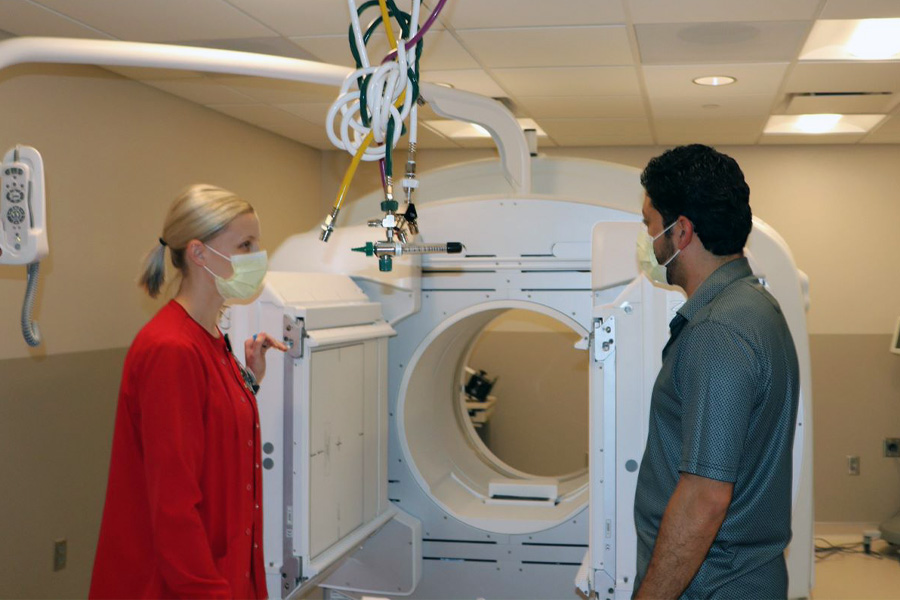 A female health care worker shows medical equipment to a male job shadow student