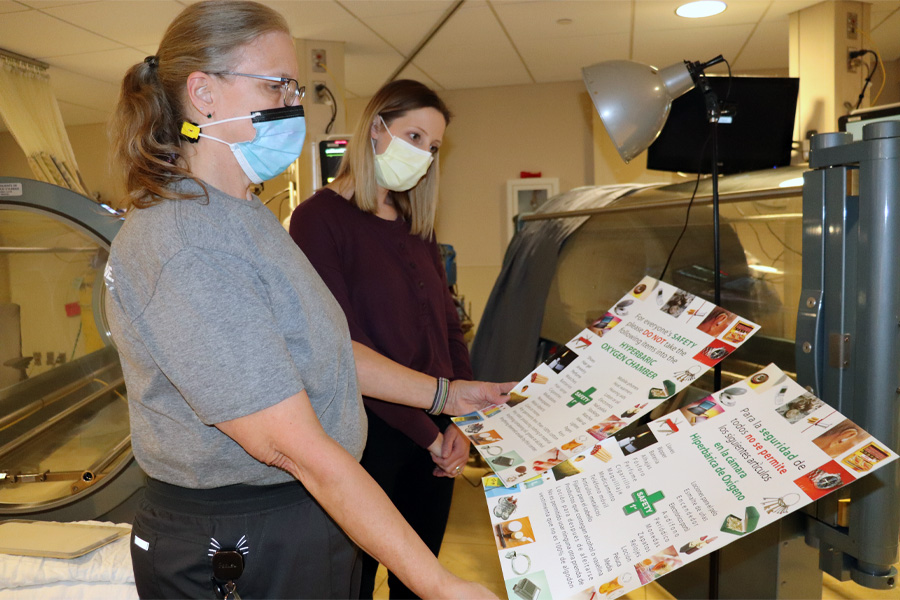 A female health care worker shows posters to a female job shadow student 