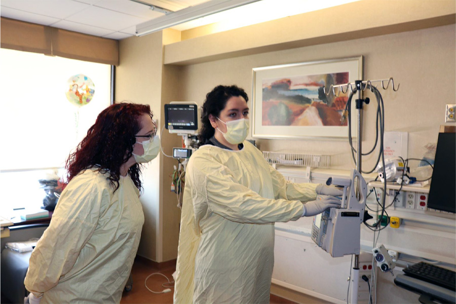 A female job shadow student observes a female health care worker in a patient room