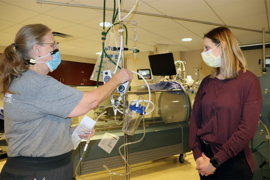 A female health care worker demonstrates equipment for a female job shadow student