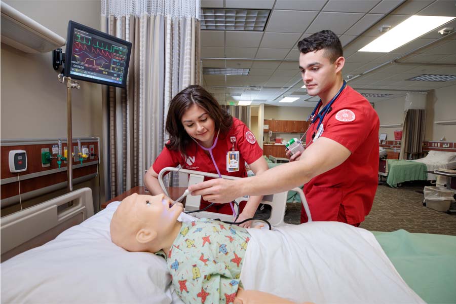 Two nursing students work with a mannequin