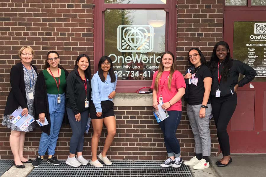 Seven people pose in front of OneWorld Community Health Center