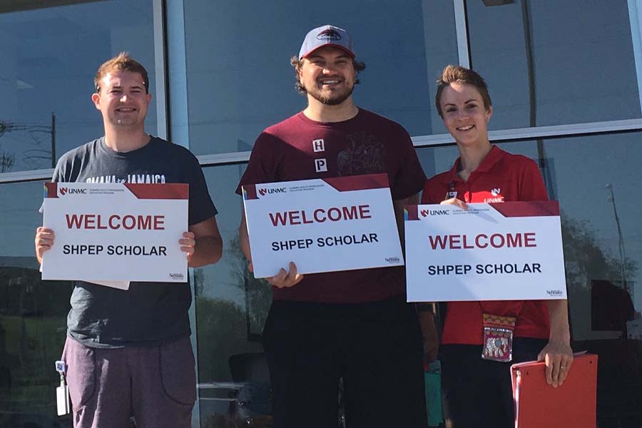 Three people hold signs that say "Welcome SHPEP Scholar"