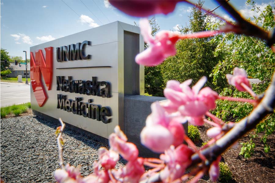 A sign for UNMC/Nebraska Medicine surrounded by flowers