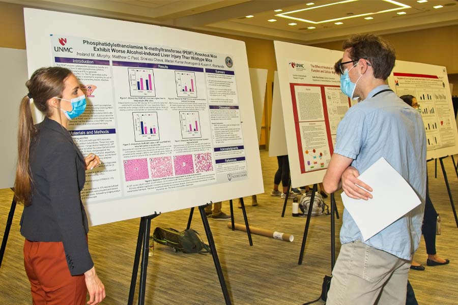 A female student presents her research while a man observes