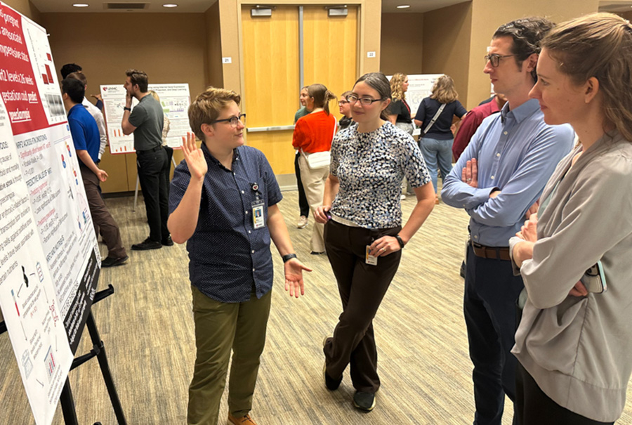 A student stands in front of a poster presentation of research