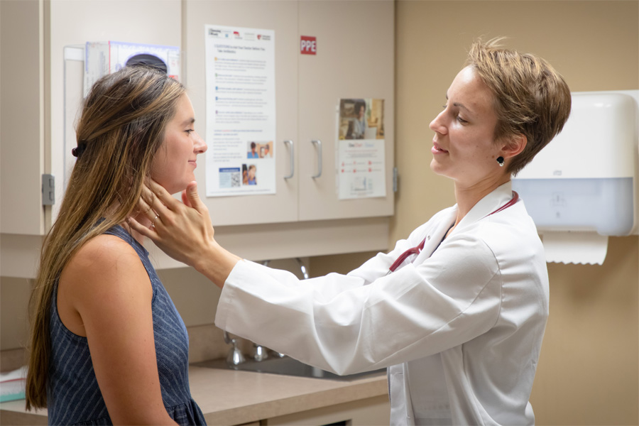 A female doctor in a white coat works with a female patient