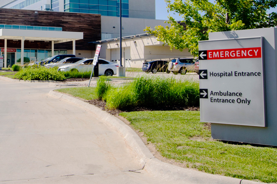 An outdoor sign with arrows reads "Emergency," "Hospital Entrance," and "Ambulance Entrance Only"