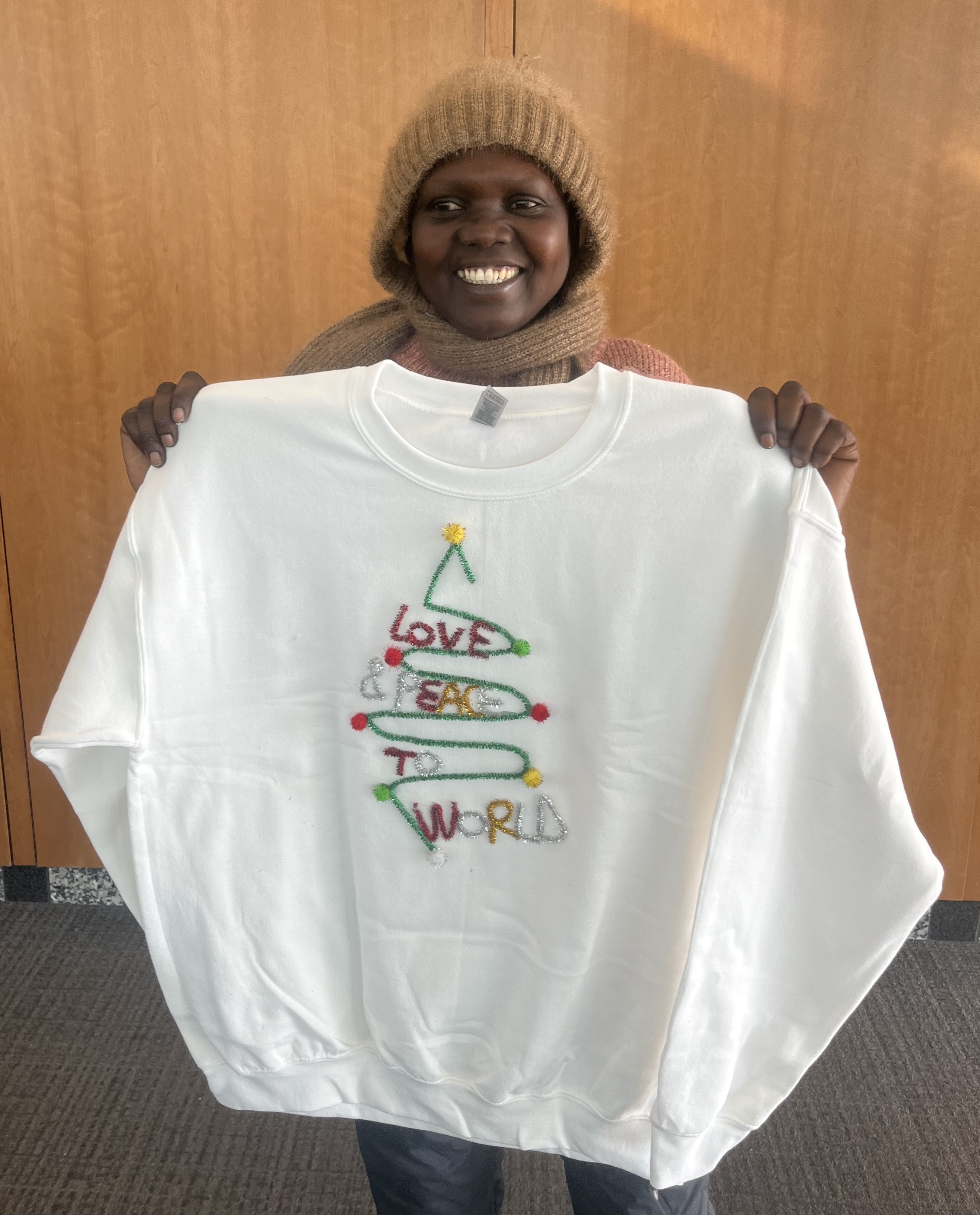 student with her sweater decorated with a tree, star, and the words peace and love
