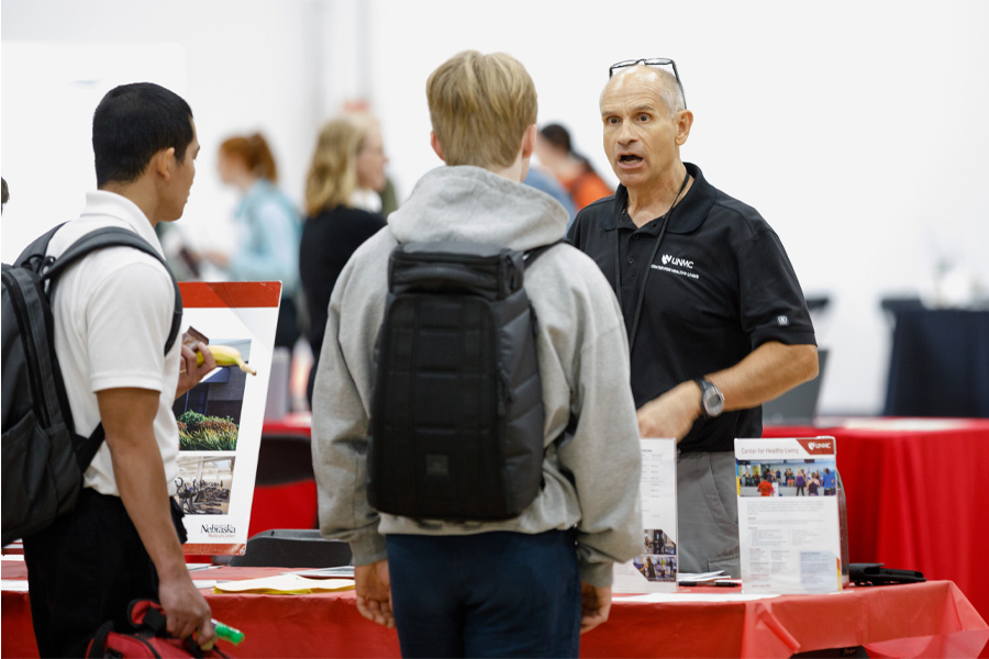 A team member from the Center for Healthy Living speaks with UNMC students at an informational booth