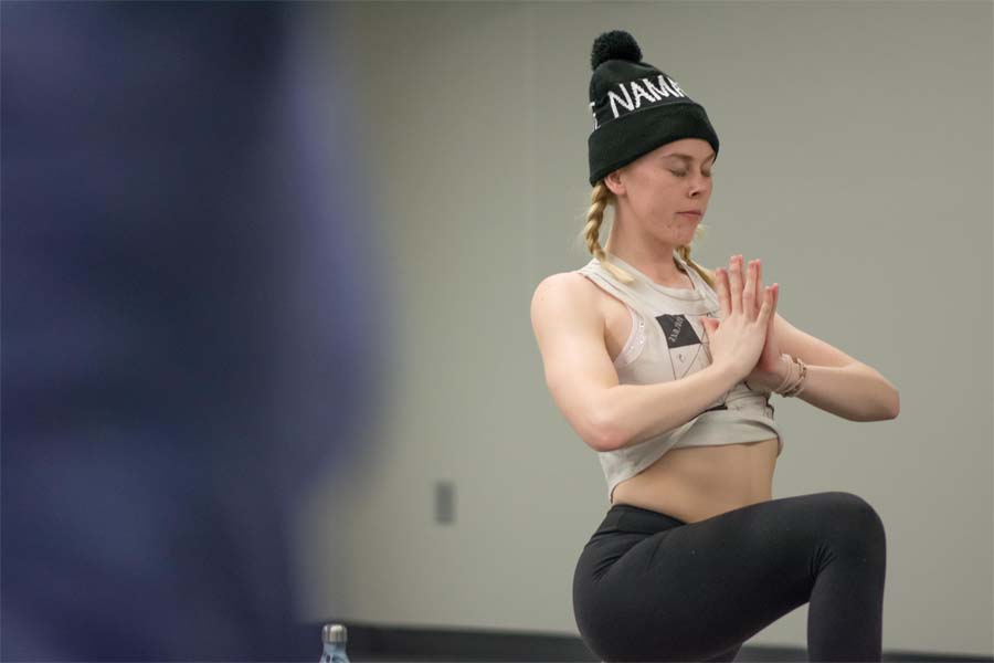 A woman in a beanie holds a yoga pose
