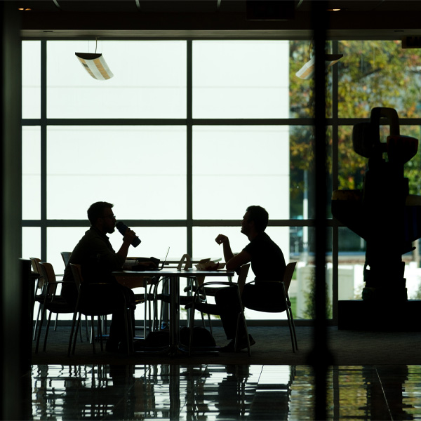 Two students sitting at a table are outlined against a window