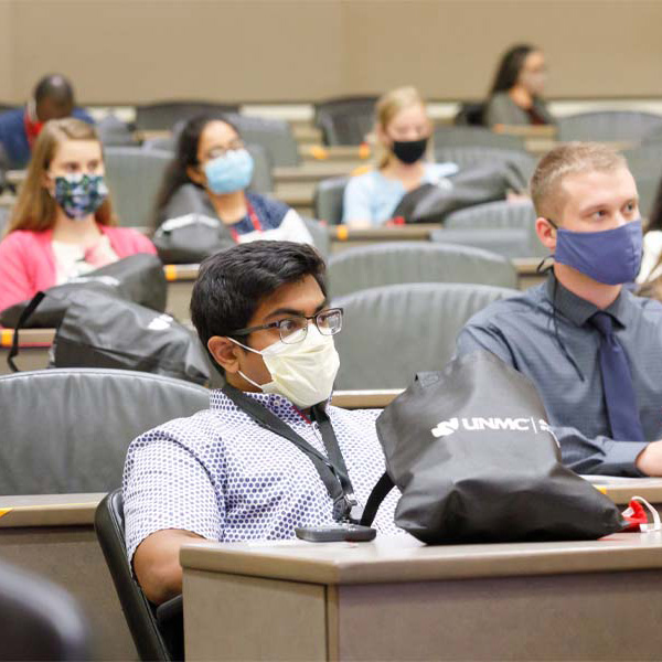 Students wearing masks sit in a lecture hall