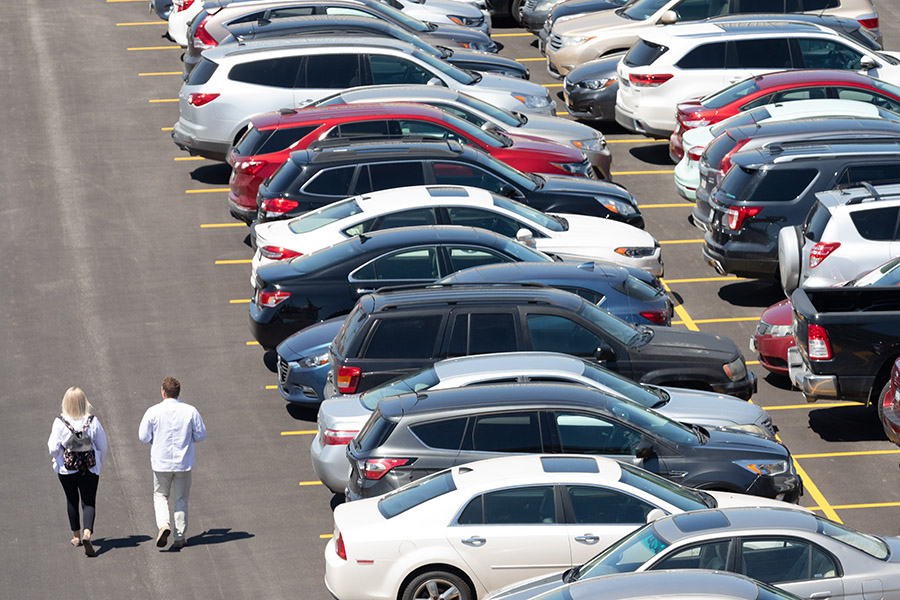 two students walking past parked cars in a campus parking lot