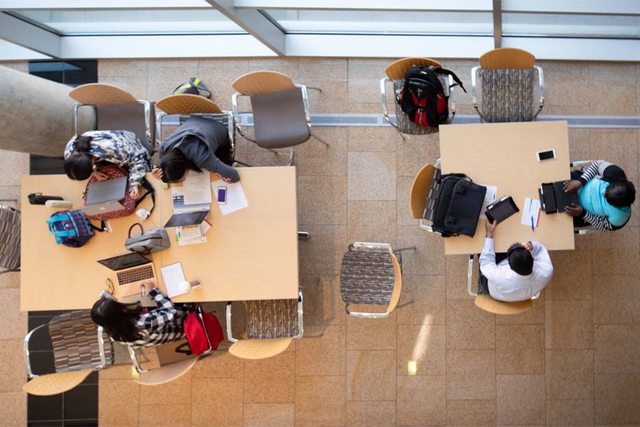An overhead view of five students studying at tables