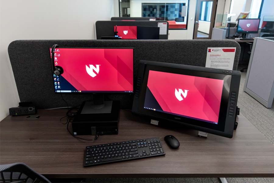 Two computer monitors with red backgrounds and the UNMC logo