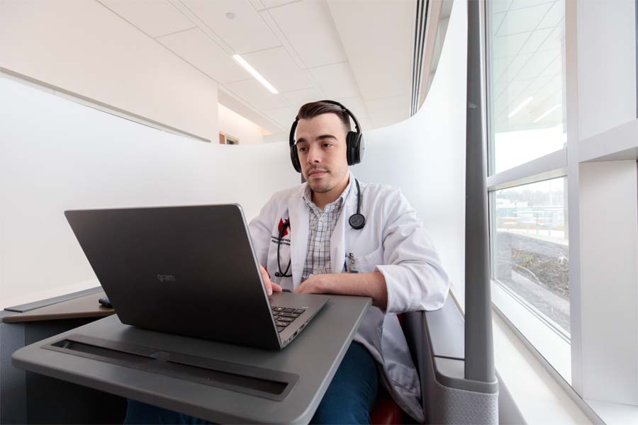 male student working at a laptop wearing headphones