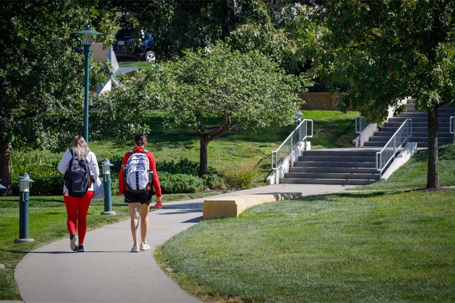 Two students with their backs to the camera walk on UNMC's campus