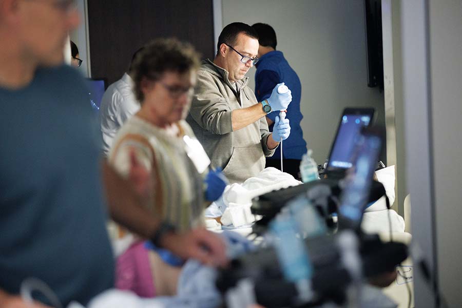 A surgeon stands amid other busy staff members in an emergency room.
