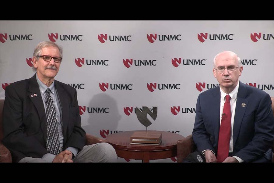 Steve Wengel, MD, and Jeffrey Gold, MD, sit in front of a UNMC-branded background