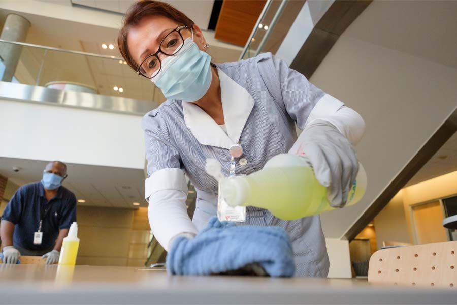 Two sanitation workers clean tables at UNMC