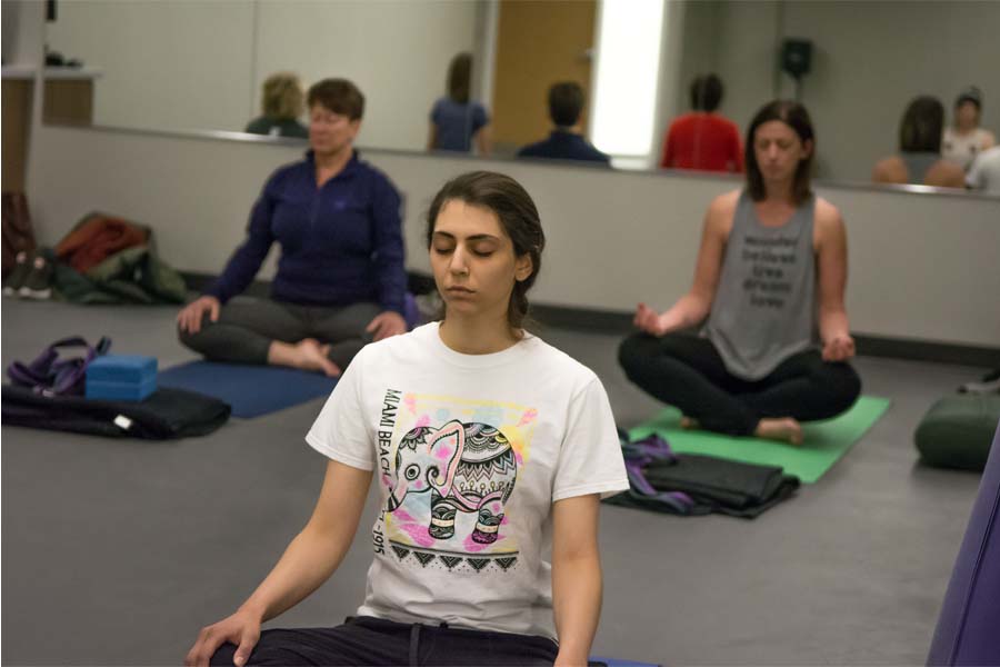 A group of people close their eyes while sitting in a yoga pose