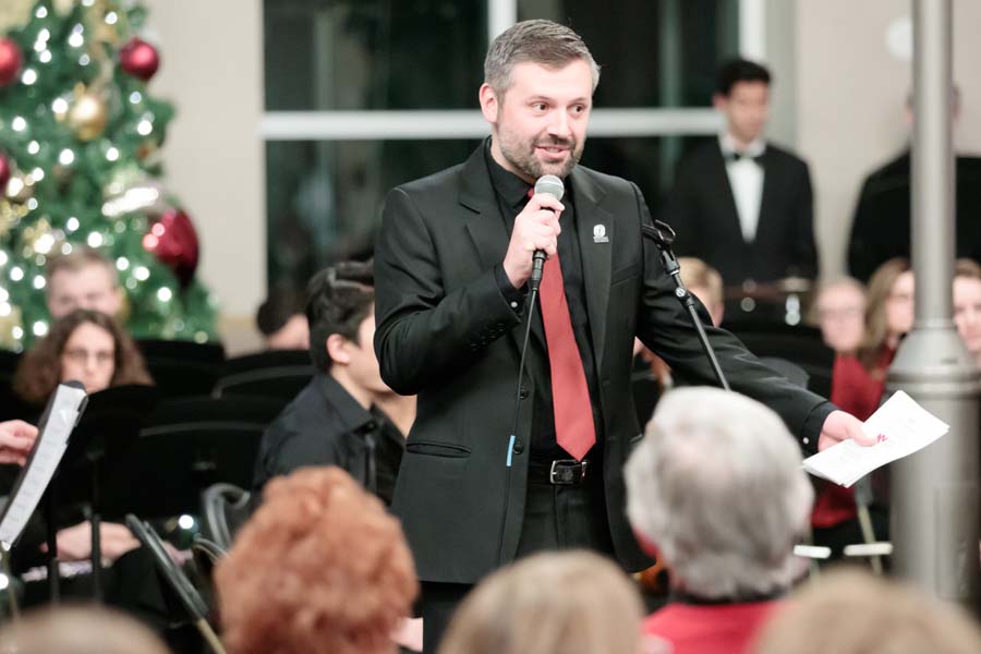 Matthew Brooks speaks to the audience at a Nebraska Medical Orchestra performance